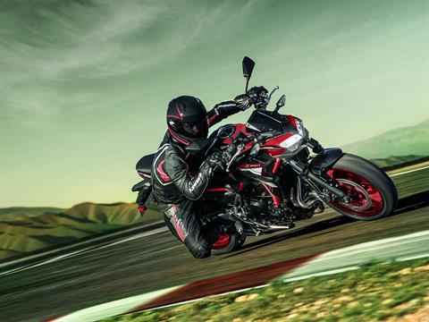 Pilote au guidon pour le test Kawasaki Z650 A2 sur circuit, posant le genou dans un virage serré