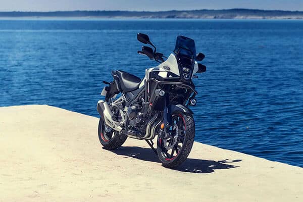 Test Honda NX500 A2 2025 : garée sur un quai en bois au bord de l'eau, vue de trois-quarts avant