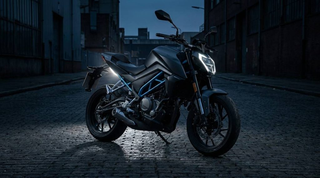 Roadster naked A2 de petite cylindrée à cadre treillis, sur rue urbaine déserte au crépuscule, ambiance charbon et accent bleu électrique.