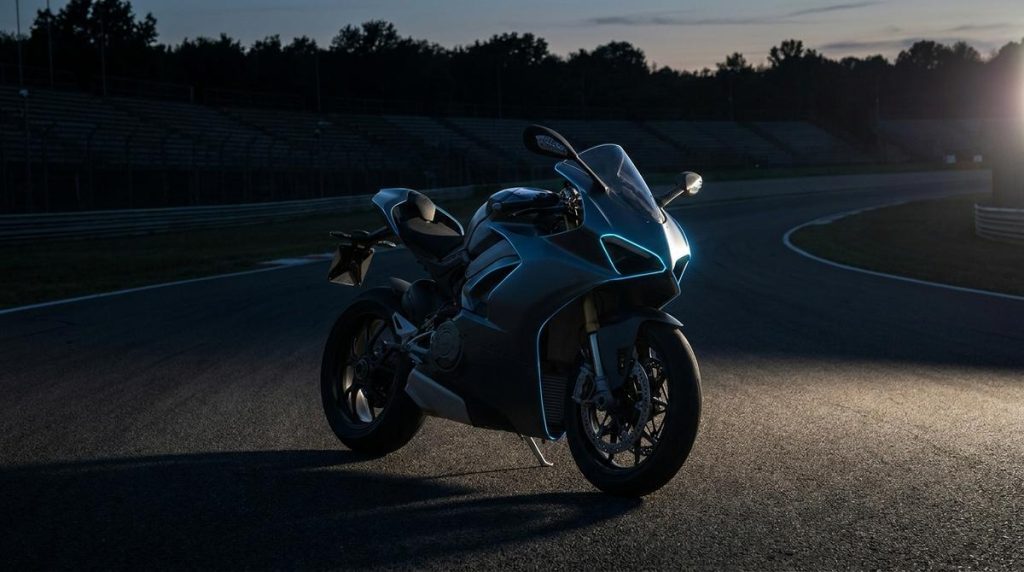 Sportive carénée de petite cylindrée accessible en A2, ambiance charbon et bleu électrique, sur route déserte au crépuscule.